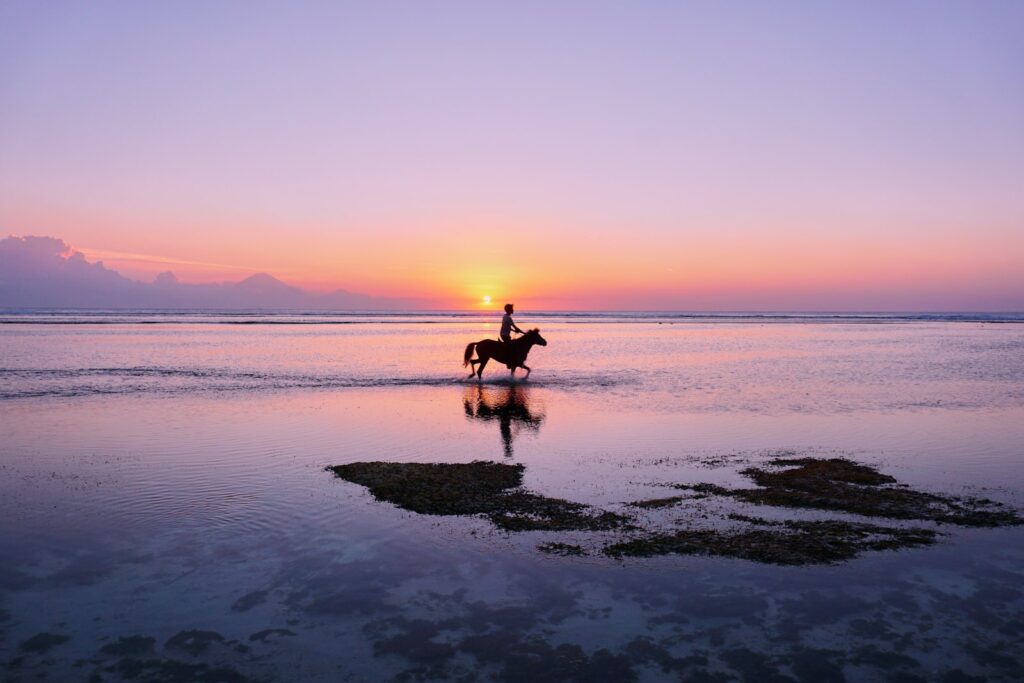 Person riding a horse along the shoreline on Gili Trawangan