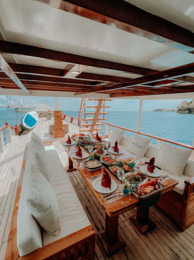 Dining setup on the Gandiva with a view of Komodo National Park, featuring an array of dishes.