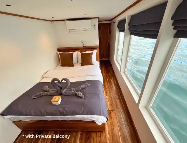Interior of the master cabin on the Lanakila Phinisi, featuring a private balcony and scenic views.